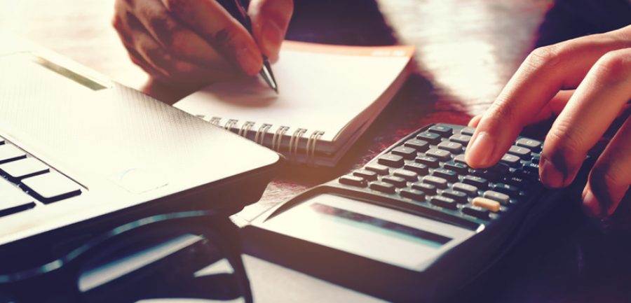 Close up woman hand using calculator and writing make note with