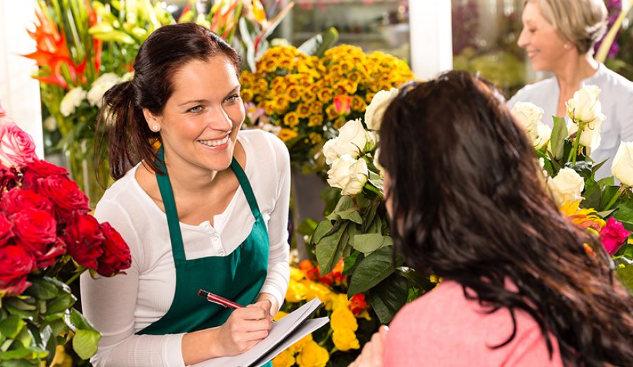 Happy florist writing flower shop talking customer