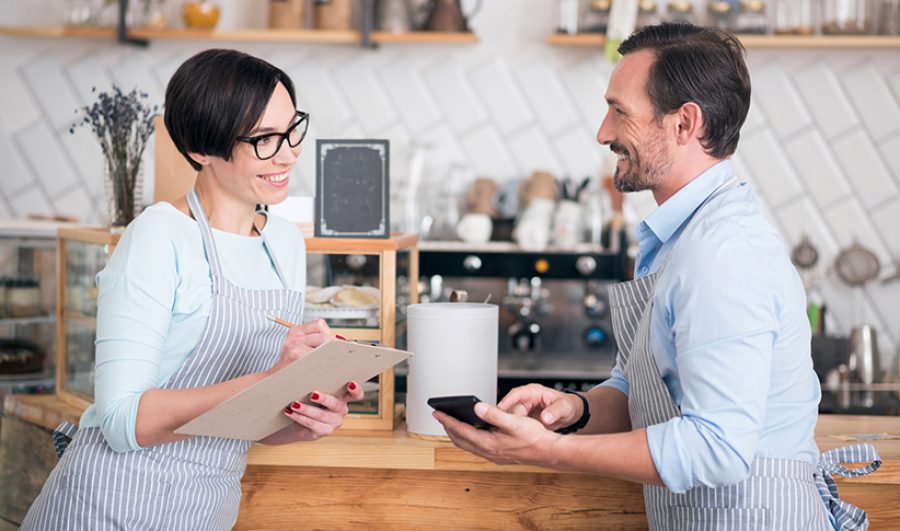 Two business owners in aprons working in cafe