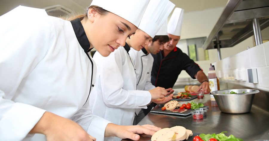Team of young chefs preparing delicatessen dishes