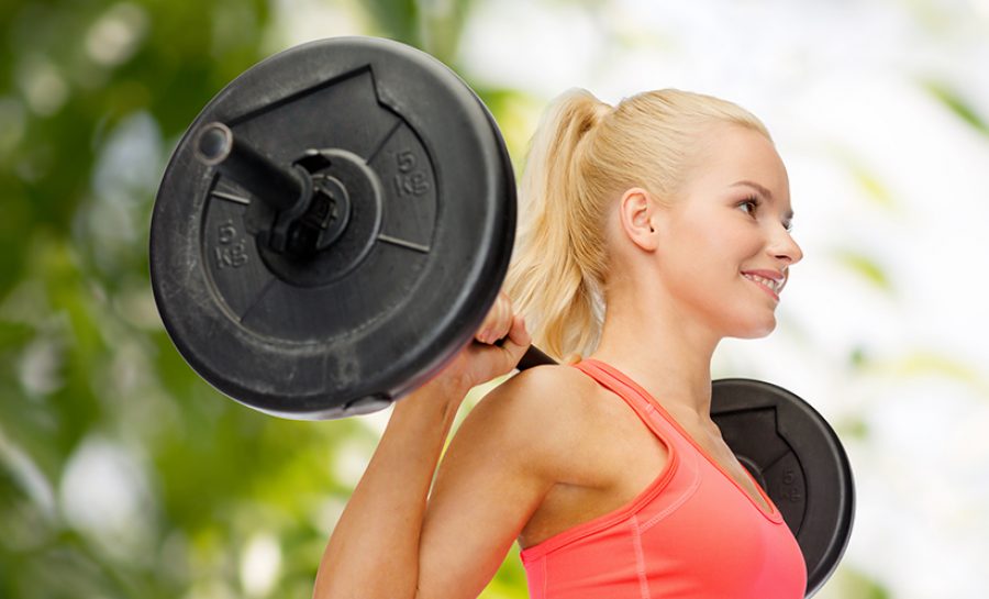 smiling sporty woman exercising with barbell