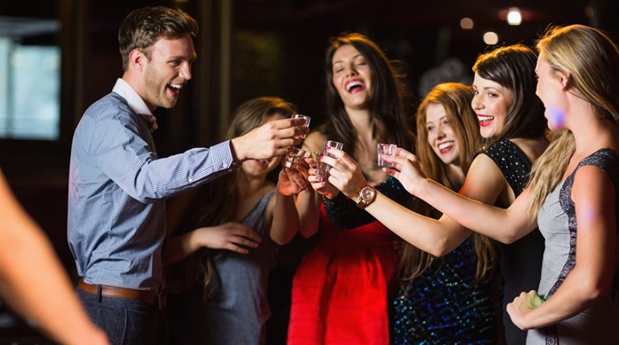 Happy friends drinking shots by the dj booth at the nightclub