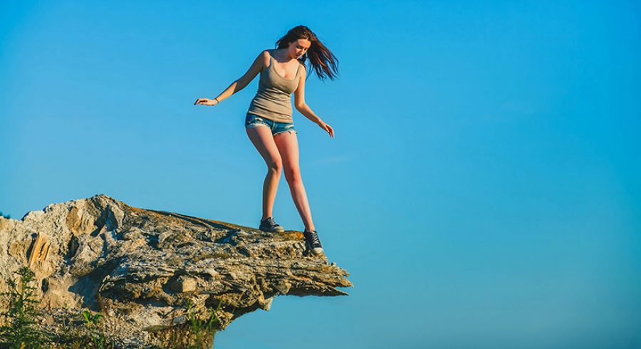 acrophobia woman tall stands on top of a rock cliff edge and is