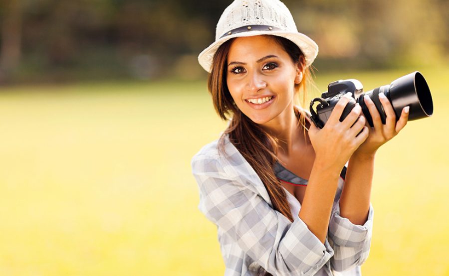 attractive young woman holding camera outdoors