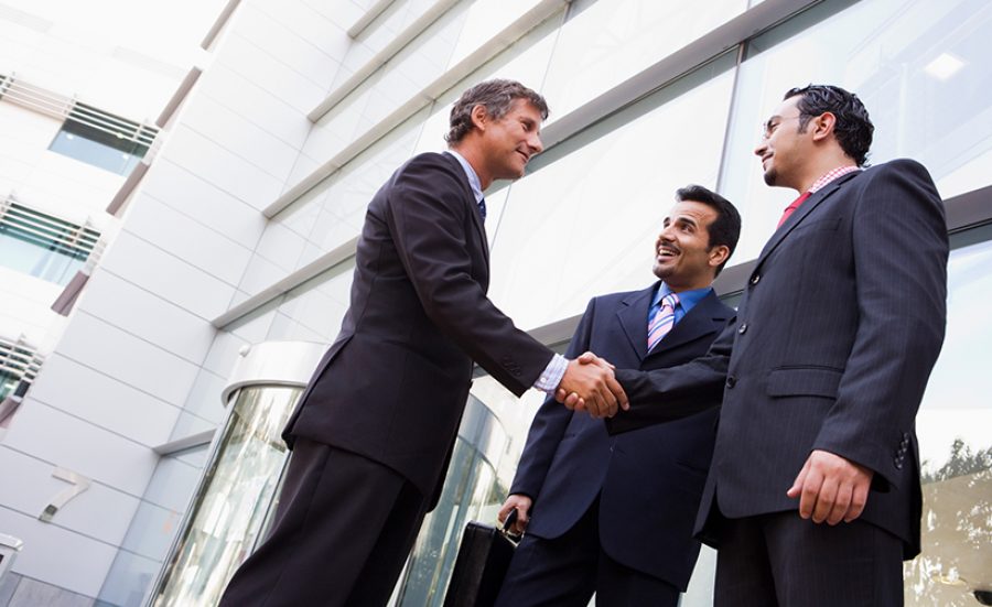 Group of businessmen shaking hands outside office