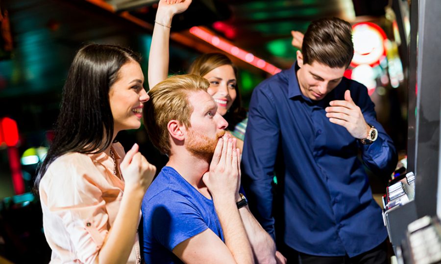 Friends gambling in a casino playing slot and various machines