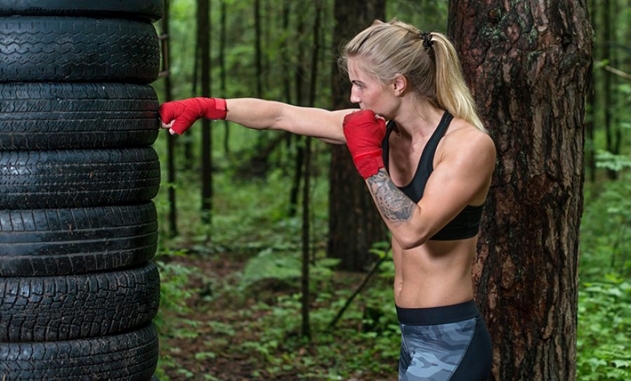 Woman boxer doing cross kick working out outdoors