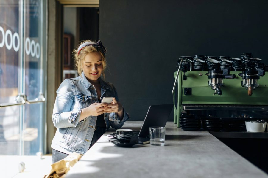 Young woman in coffee shop, using smartphone, taking pictures model released Symbolfoto property released PUBLICATIONxIN